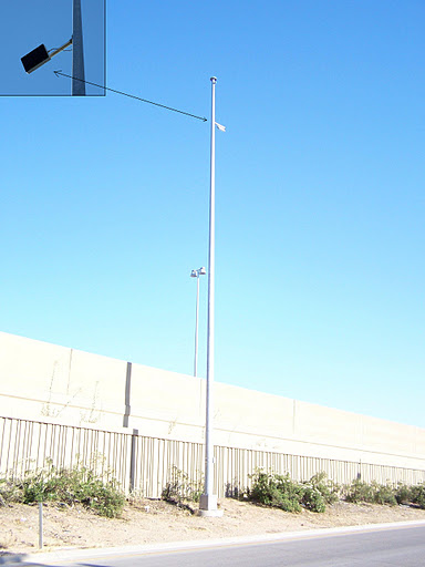 A tall, empty pole with an attached passive acoustic device stands next to a freeway.