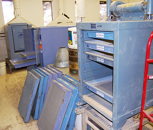 A materials testing lab for ADOT with blue drying racks and mesh screens stacked on the floor.