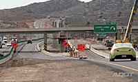 Cars drive on a divided highway near a construction zone with orange warning signs, cones, and an exit sign for Cordes Lakes, surrounded by hills.