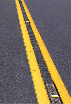 Close-up of a road with double yellow lines and recessed pavement markers