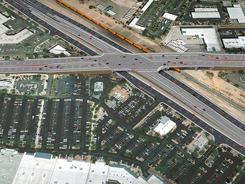 Aerial view of a busy highway interchange with many cars and nearby parking lots and buildings.