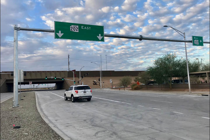 Vehicle passes under sign for new freeway interchange.