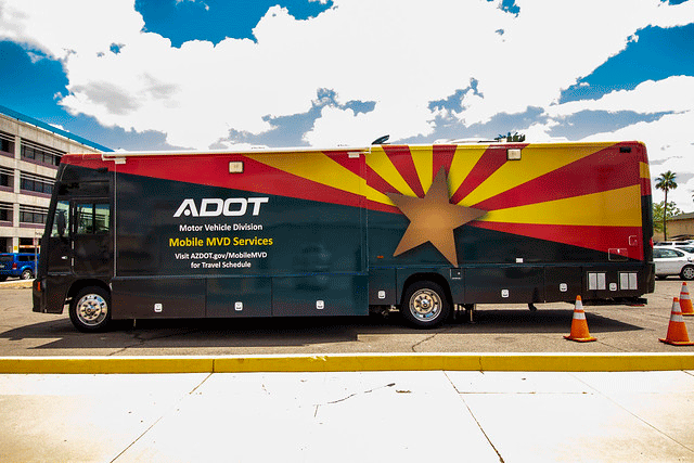 A colorful ADOT Mobile MVD Services unit is parked in a parking lot, decorated with the Arizona state flag design.