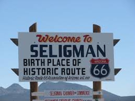 A large sign reads Welcome to Seligman, Birth Place of Historic Route 66 with mountains and blue sky in the background.