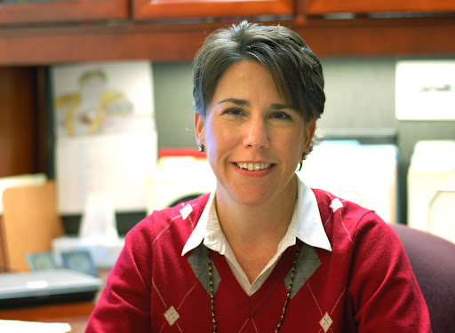 A woman at her desk poses for a photo.