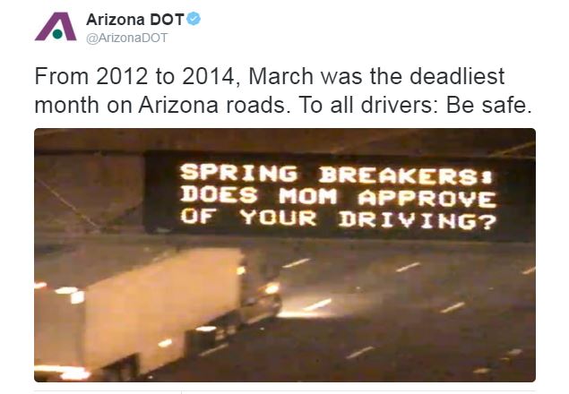 Highway sign displays SPRING BREAKERS! DOES MOM APPROVE OF YOUR DRIVING? with a truck passing by, highlighting a road safety message from Arizona DOT.