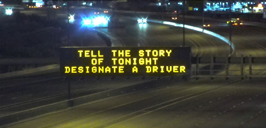 A digital message board over a highway encourages safe driving.