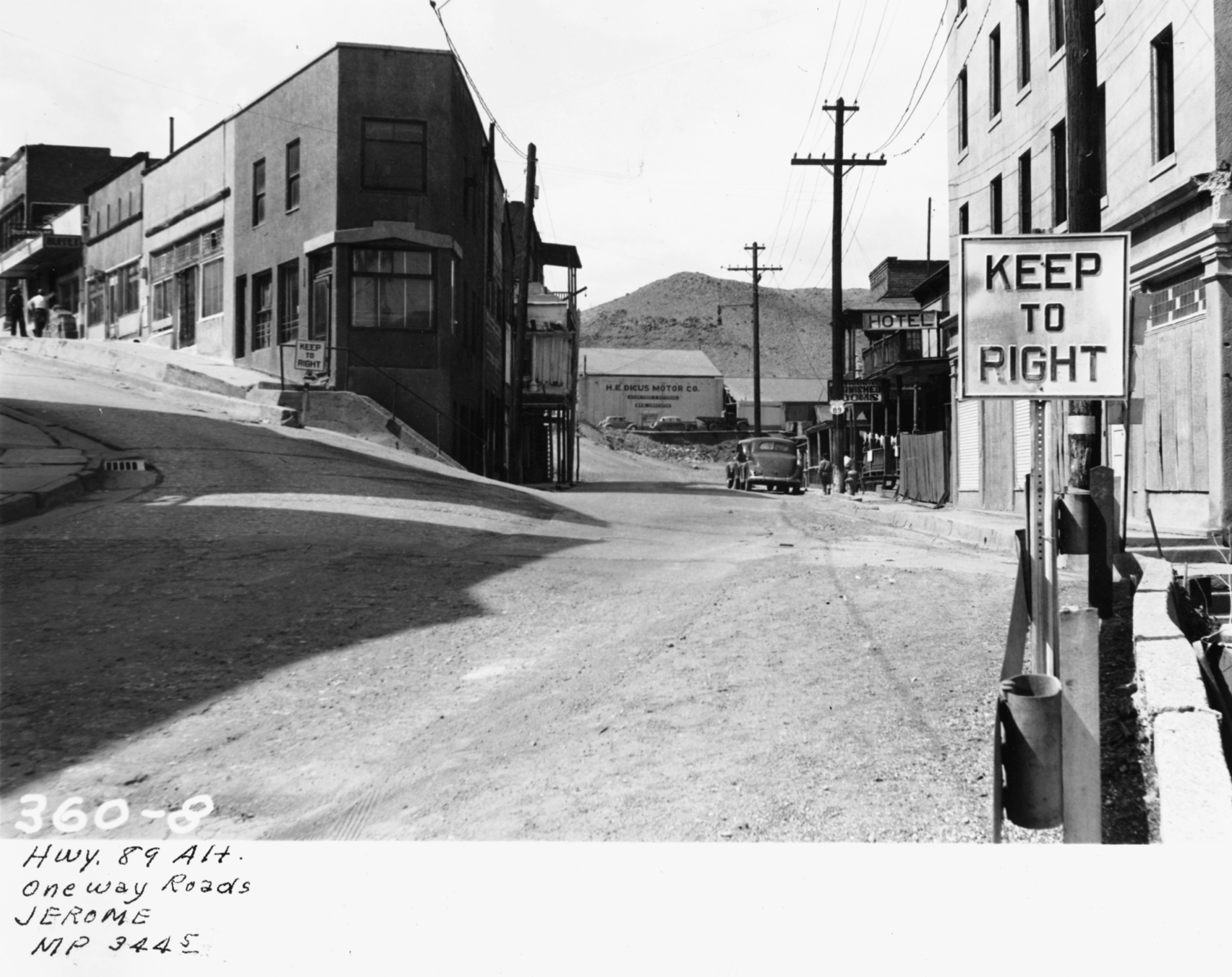 Black and white photo of a street in Jerome, Arizona, showing buildings, telephone poles, a KEEP TO RIGHT sign, and handwritten notes at the bottom.