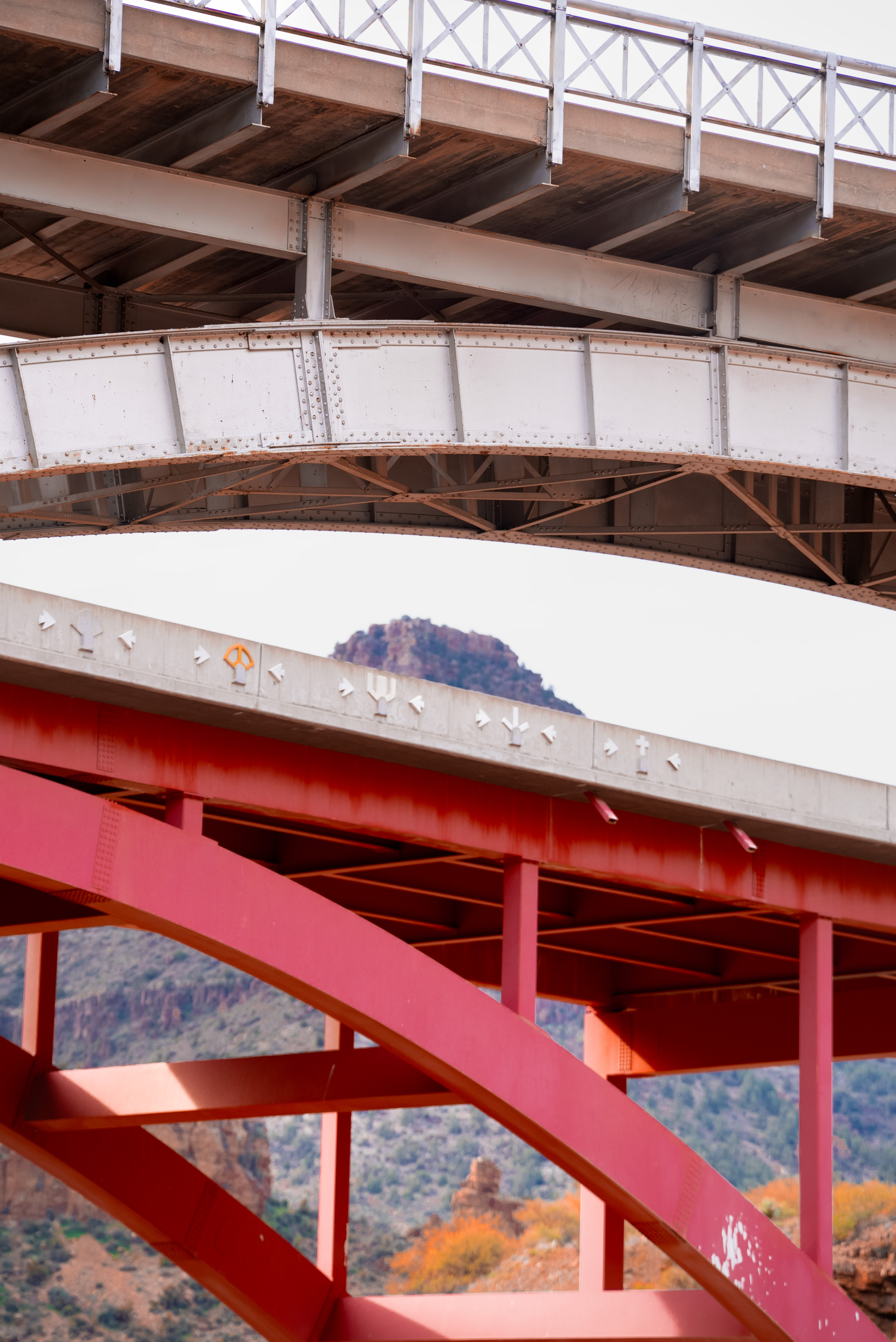 Two bridge arches overlap each other. A mountain is visible in the background through the gaps between the bridges.