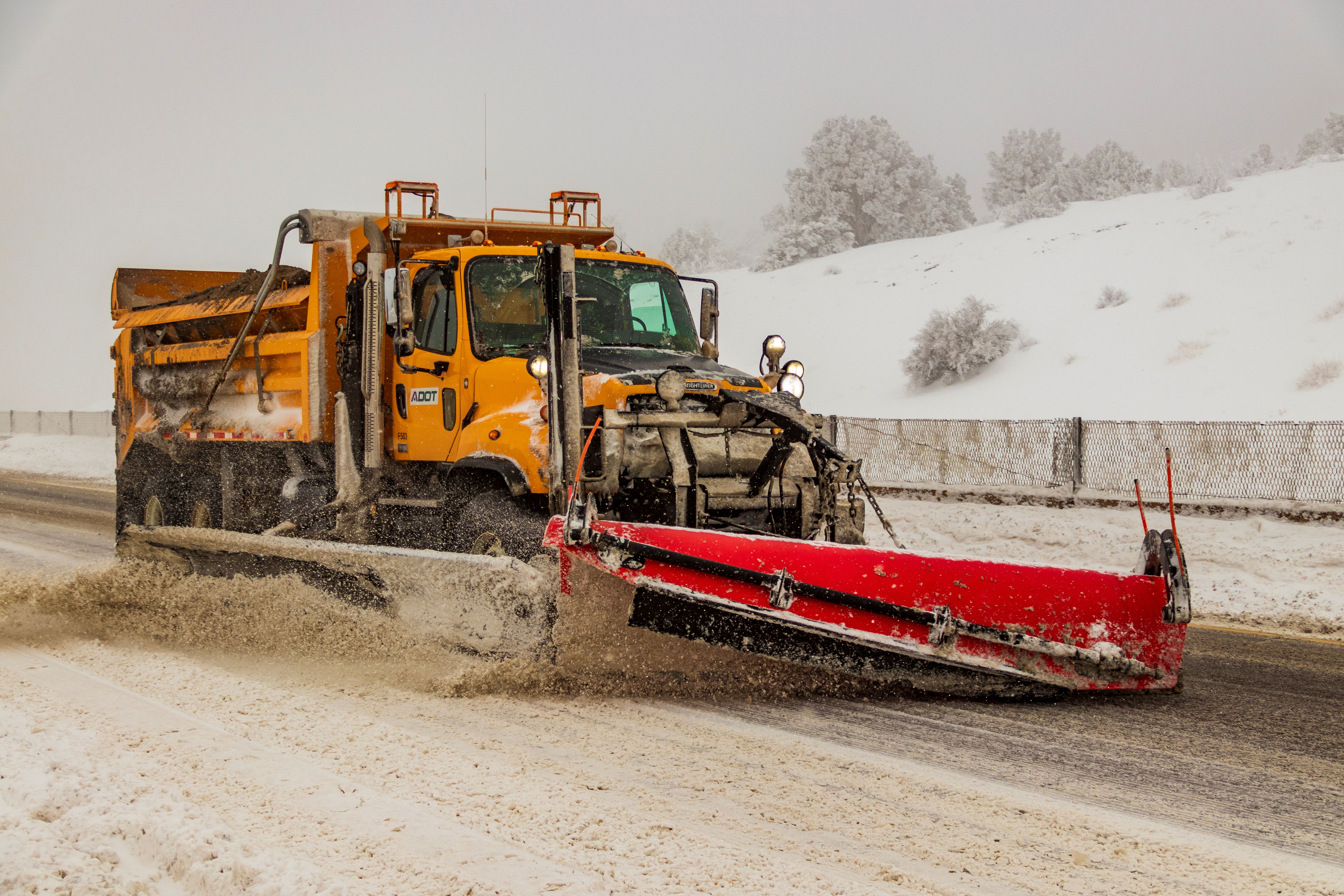 A snowplow on an icy highway plowing snow. 