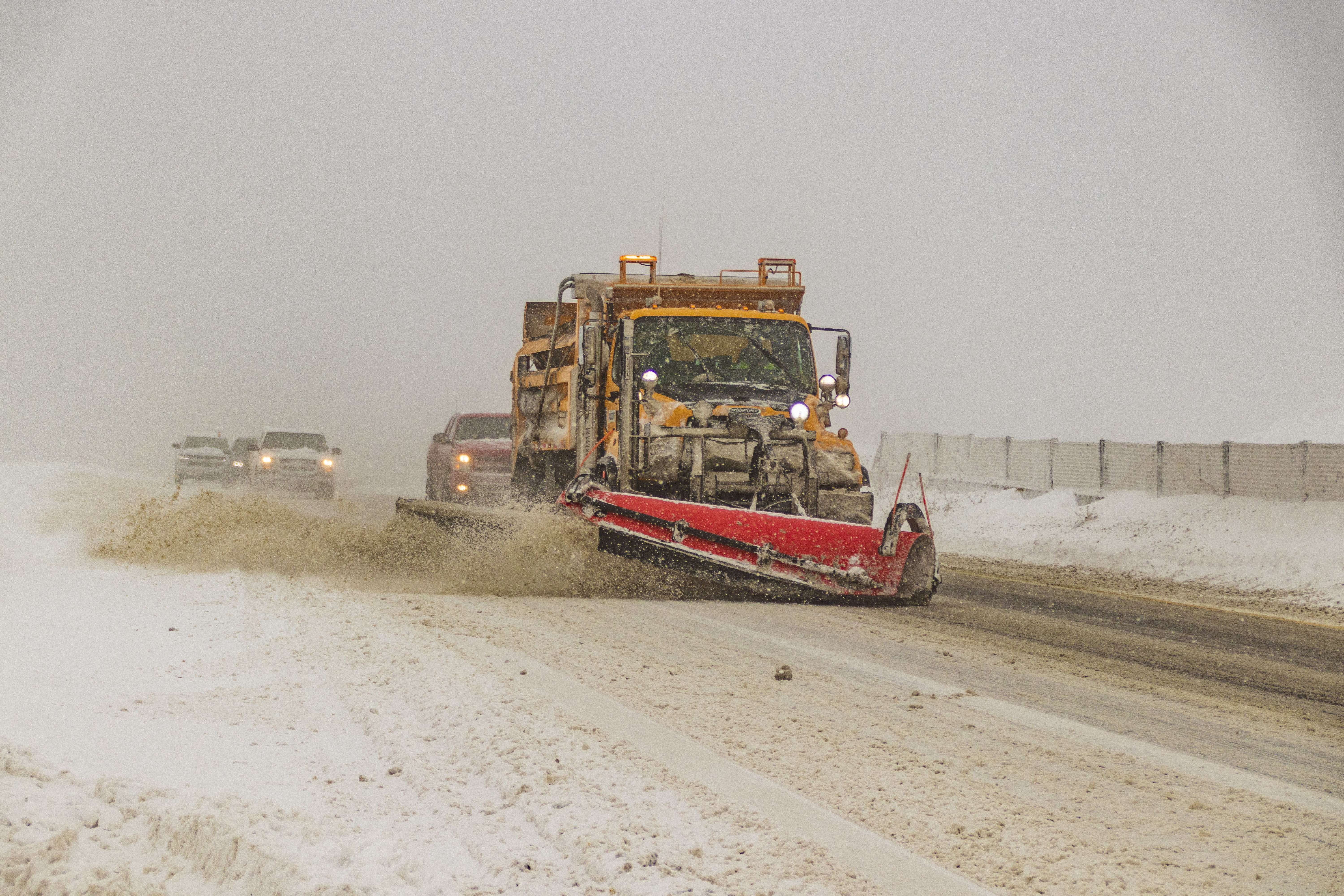 A snowplow on an icy highway plowing snow. 