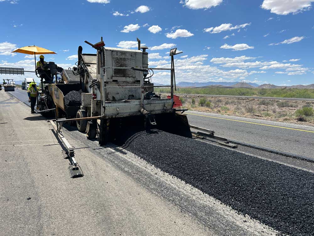 Highway workers operate an asphalt paver resurfacing Interstate 10