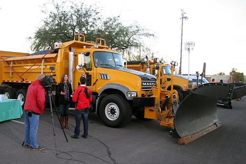 Snow plow in parking lot with interview taking place next to it
