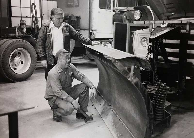 Crew members readying snow plow