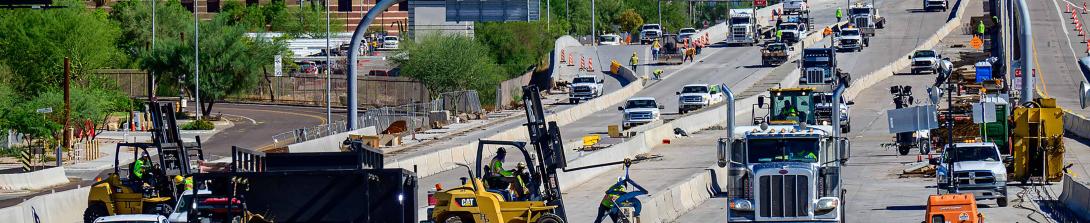 ADOT Highway construction scene with workers, vehicles, and equipment improving a divided roadway