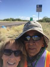 Two people standing in front of an Adopt a Highway sign on State Route 86
