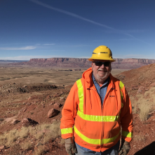 ADOT Geologist Jim Lemmon, decked out in safety gear, poses in front of a desert landscape