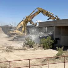 Construction heavy equipment demos a bridge.