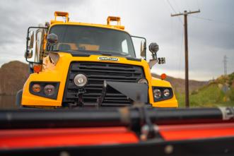 A close up of a snowplow with mountains in the background