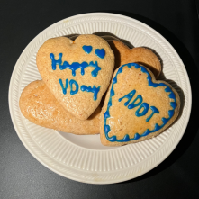 Heart shaped cookies with "Happy V-Day" and "ADOT" written on them in icing.