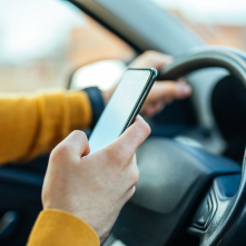 A person uses a mobile phone while driving a vehicle. 