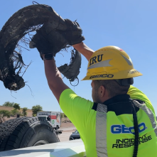 A worker putting a piece of tire debris in the back of a truck