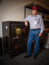 A man stands next to an old safe.