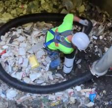 A man removes trash and debris from a pump station.