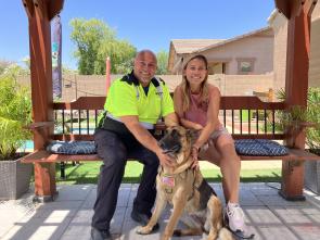 Two people pose for a picture with a dog.