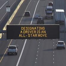 A digital message board on the highway encourages motorists to designate a driver.