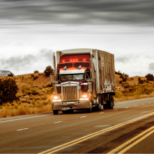 A semi-truck drivers on a rural highway.