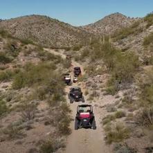 Off-highway vehicles travel together on a dirt trail.