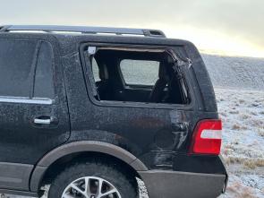 An SUV with a broken rear window after it clipped a snowplow.
