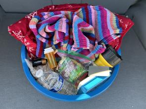 A basket filled with blankets, scarves, water, first aid kit and more