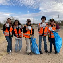 A group of students participate in an Adopt-a-Highway clean-up event along a rural highway.