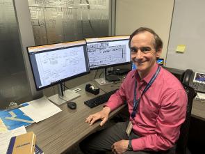 A man sitting in front of computer monitors
