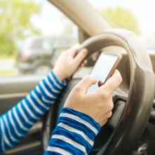 A person using a phone while driving behind the wheel.