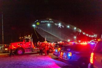 Photo of the seaplane loaded on the back of a large truck and trailer. 