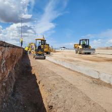 Heavy equipment operates in a highway work zone in Arizona as a man stands nearby.