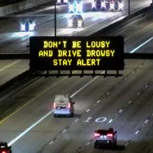 A digital message board on the highway encourages motorists to stay alert.