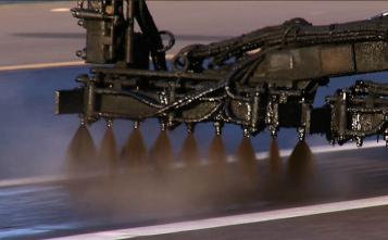 Sprayer applies fog seal to highway. 