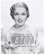 A woman wearing a chic 1930s dress holds a copper Arizona license plate from 1934.