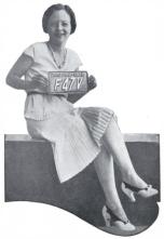 Miss Arizona 1931 holds a copper license plate. The woman is wearing a white dress and heels.