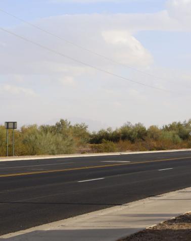 Paved section of State Route 95 between Main Street and milepost 116, showing fresh asphalt, lane striping, and desert vegetation along the roadside.