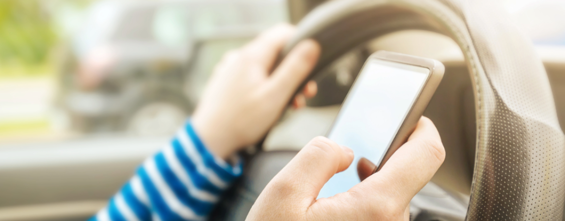 A person using a phone while driving behind the wheel.