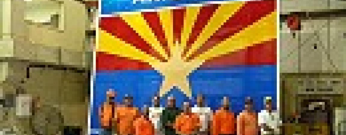 a group of people standing in front of a large Arizona sign