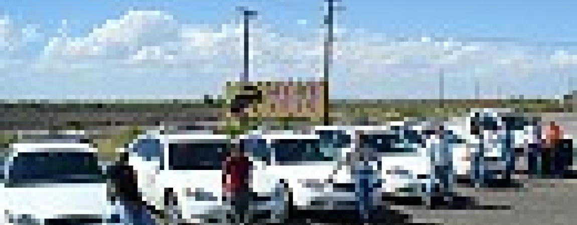 a group of cars with people standing in front of them