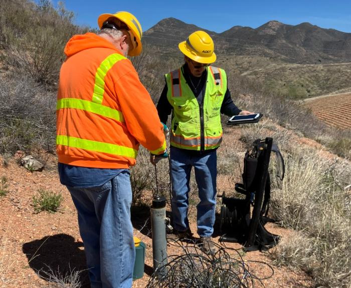 Two ADOT geotechs use an inclinometer on a hillside to measure the area's stability.