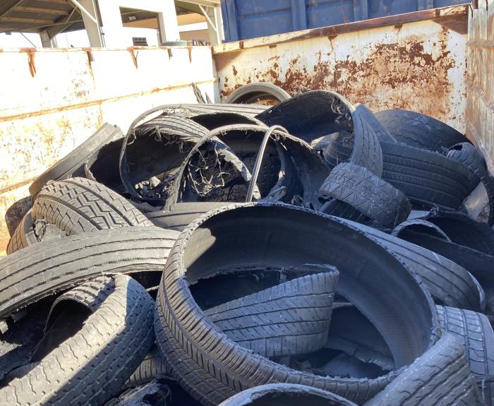 A dumpster is filled with shredded and blown-out tires.