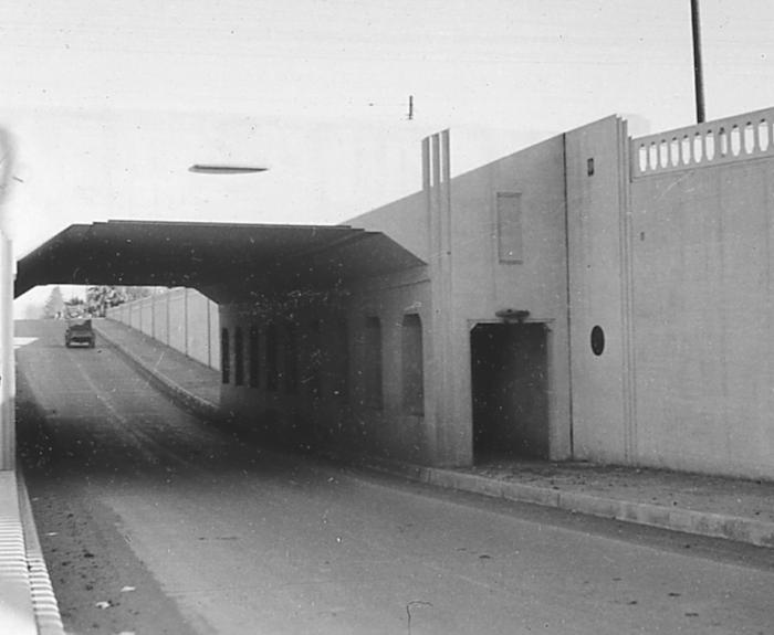 A black-and-white photo from 1936 of a vehicle driving under an underpass.